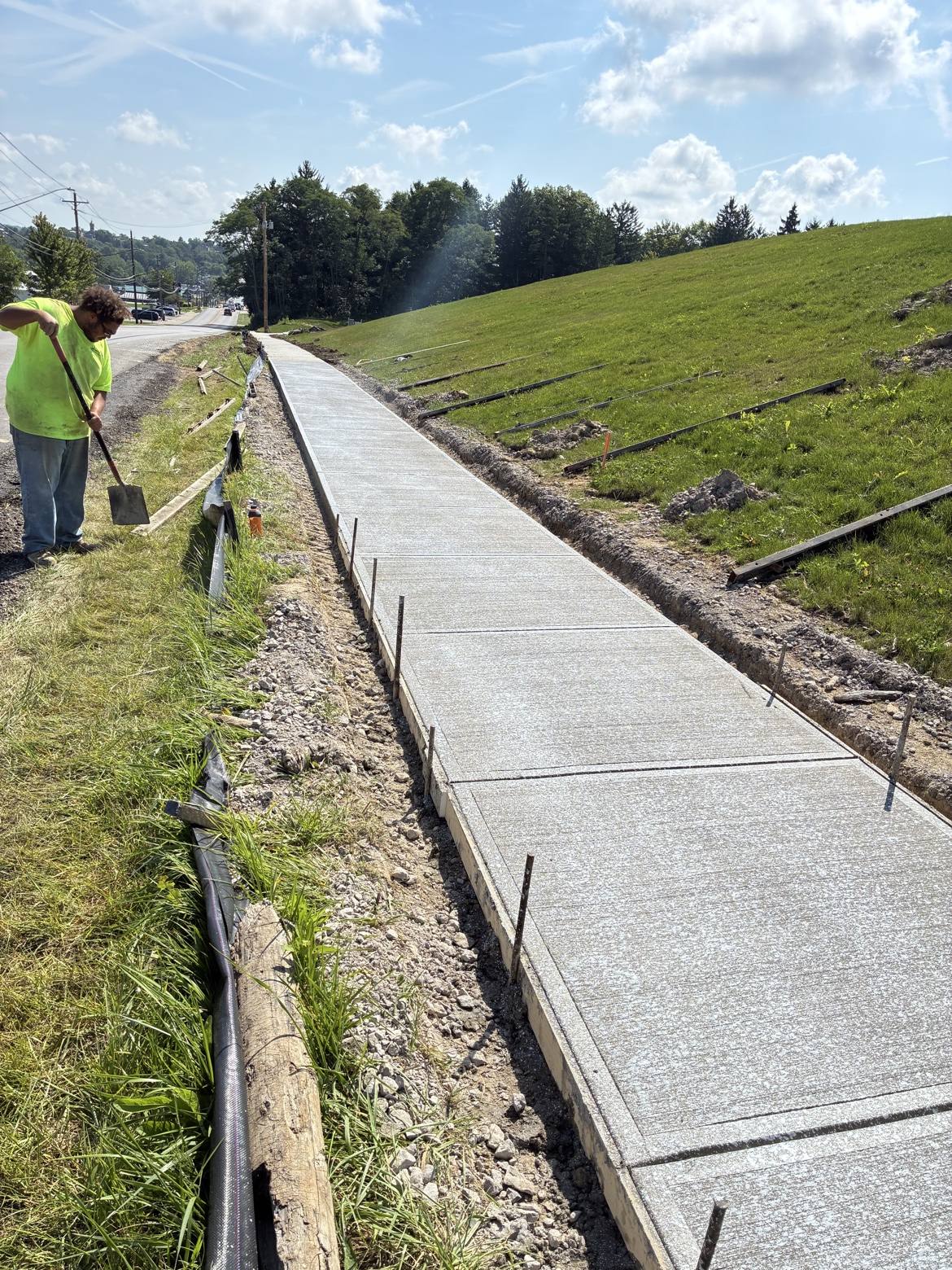 Worker beside a newly finished long concrete sidewalk