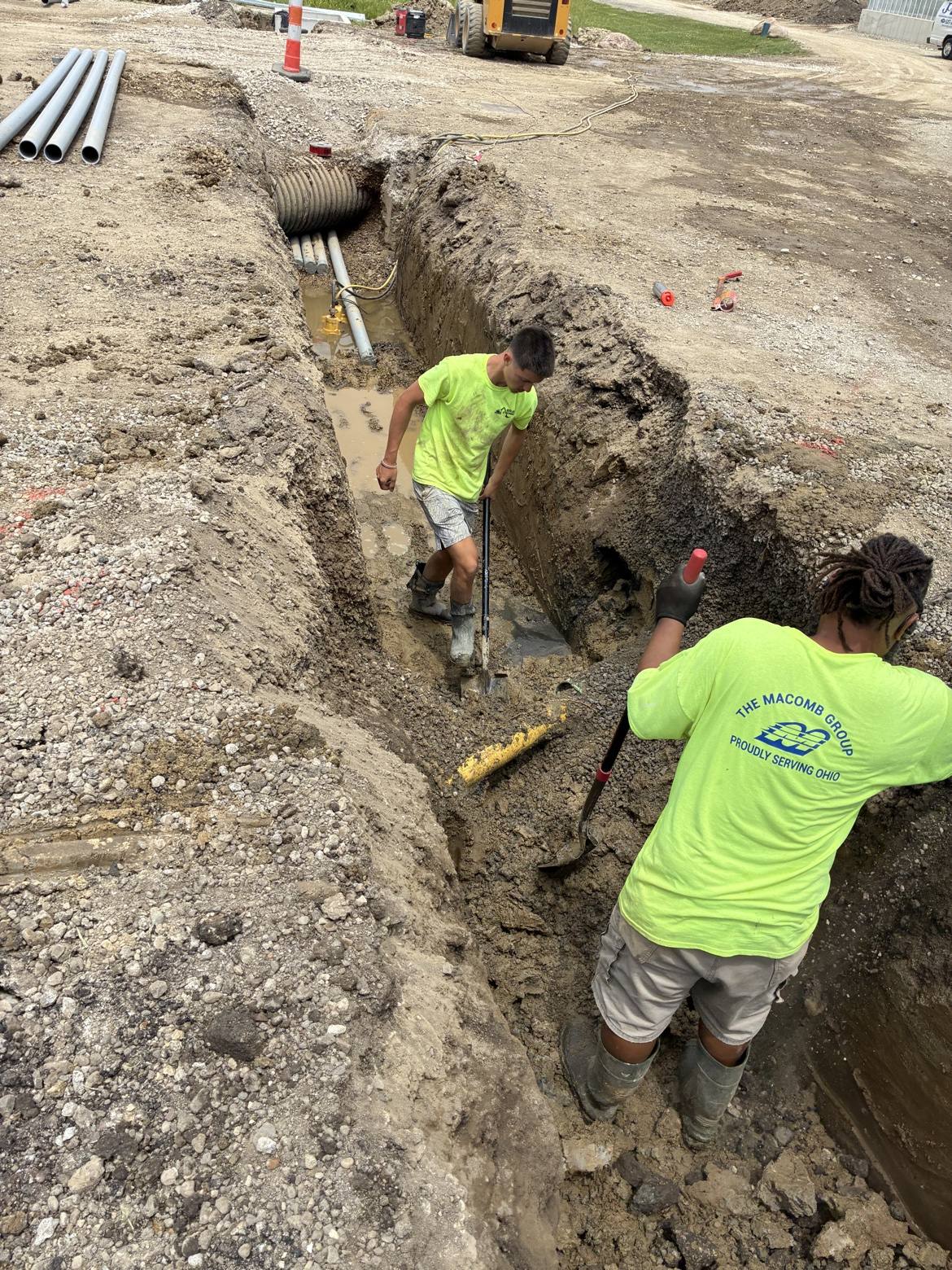 Crew digging a deep utility trench with shovels