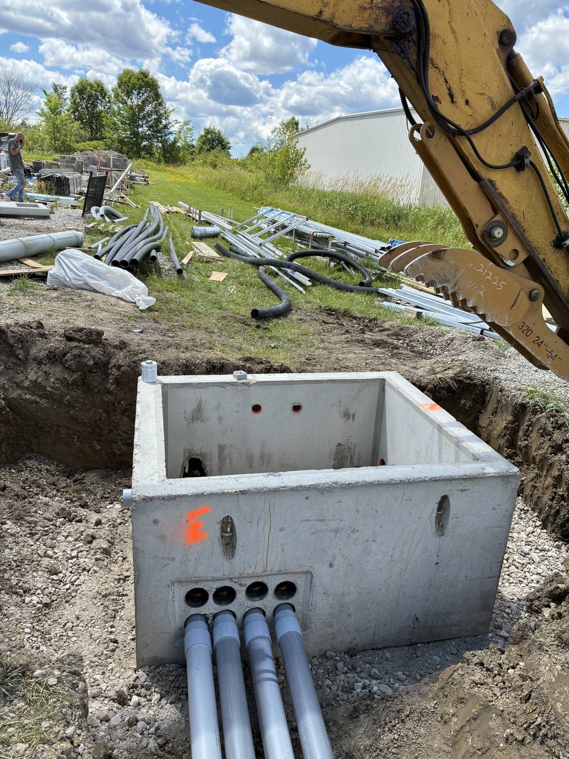 Concrete underground utility vault with conduit pipes and an excavator arm