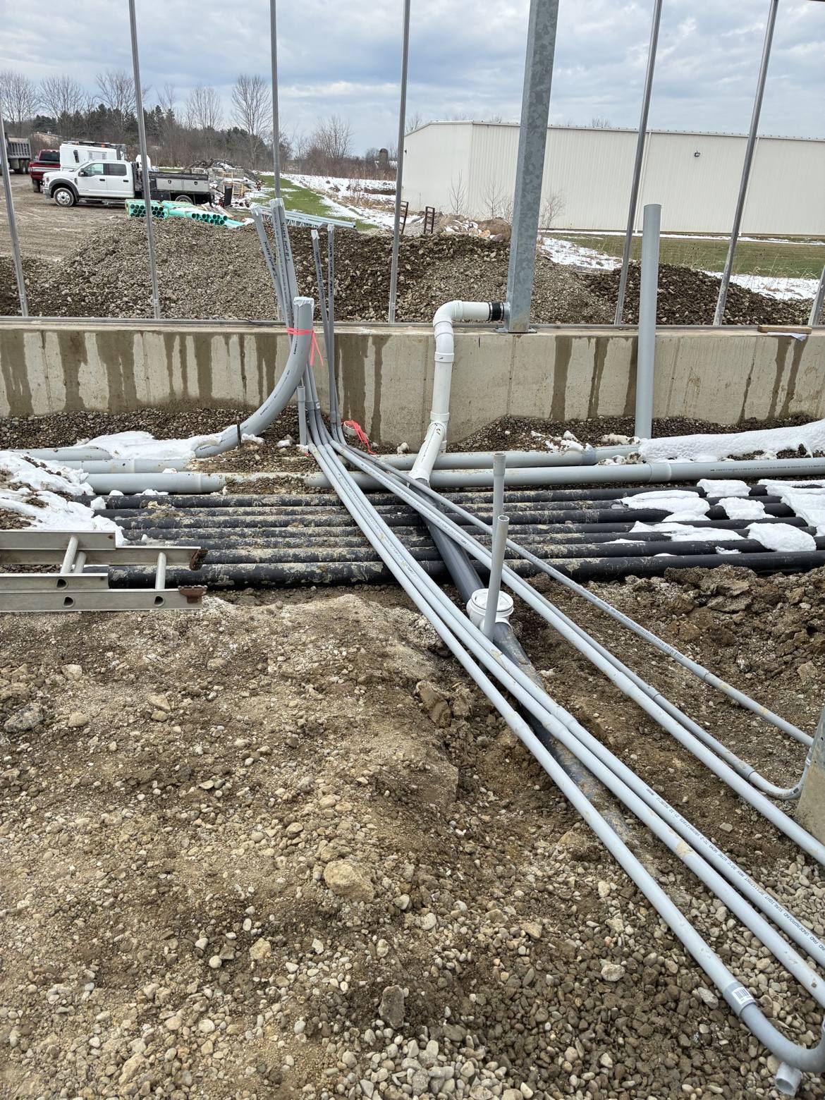 Underground electrical conduit and plumbing runs at a foundation wall