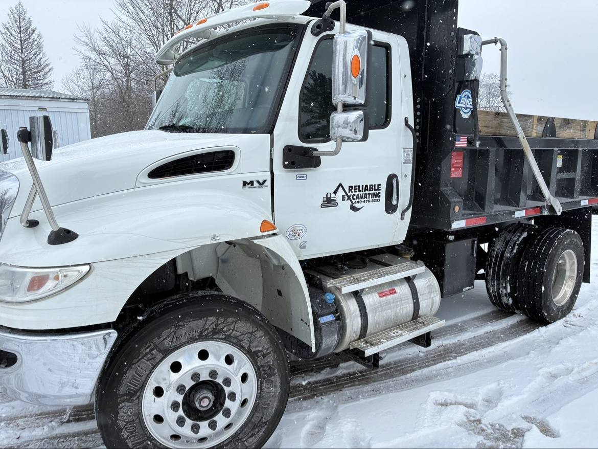 Reliable Excavating white International dump truck photographed in snow