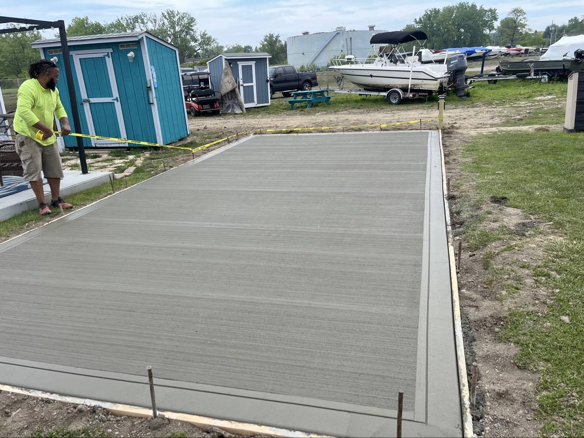 Fresh broom-finished concrete pad with a worker nearby