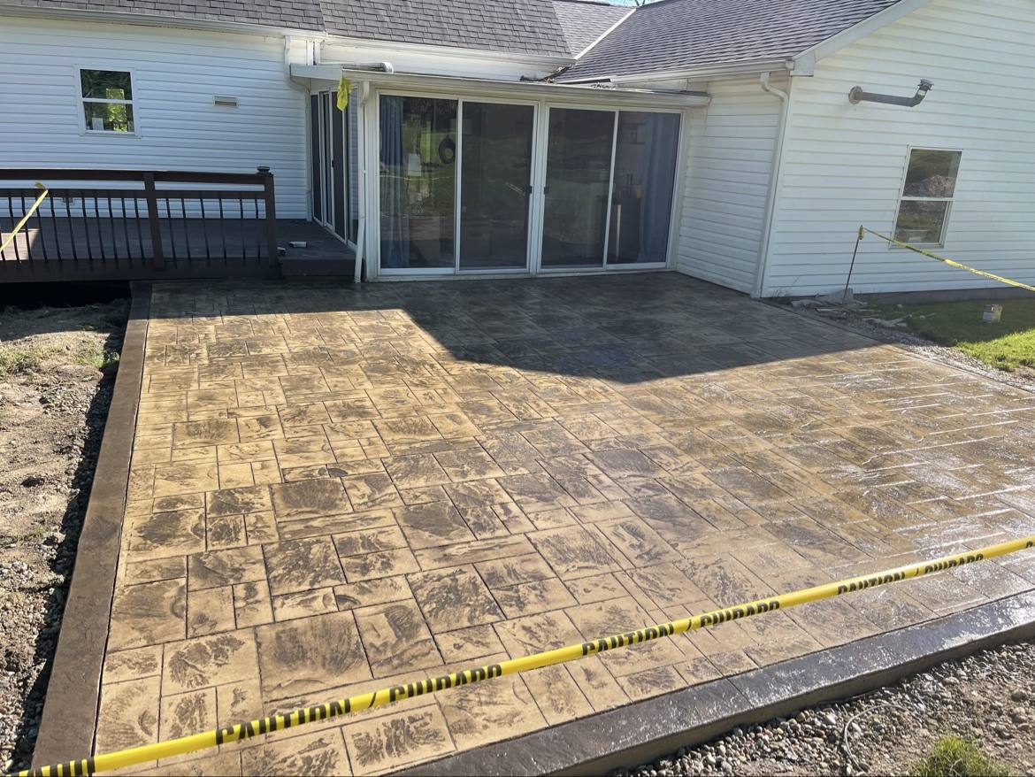 Finished stamped concrete patio in a basketweave stone pattern beside a house