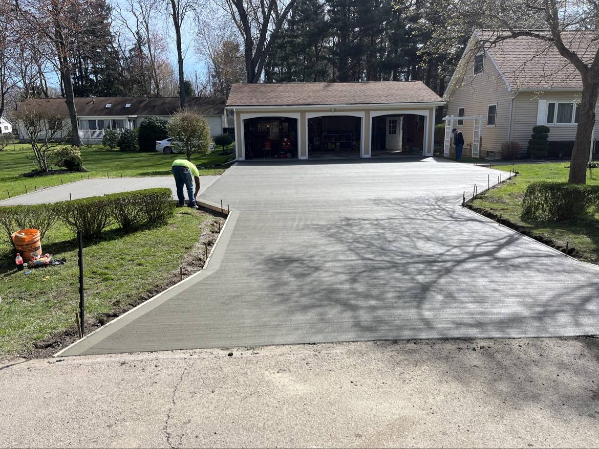 Fresh concrete driveway being finished in front of a three-car garage