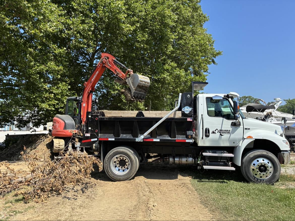 Mini excavator loading soil into the Reliable Excavating dump truck