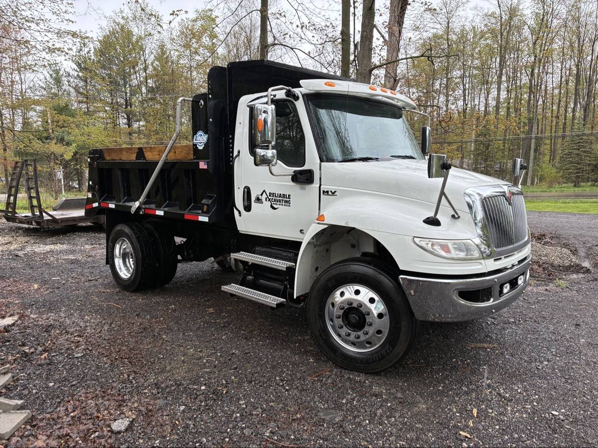White Reliable Excavating International dump truck parked on gravel